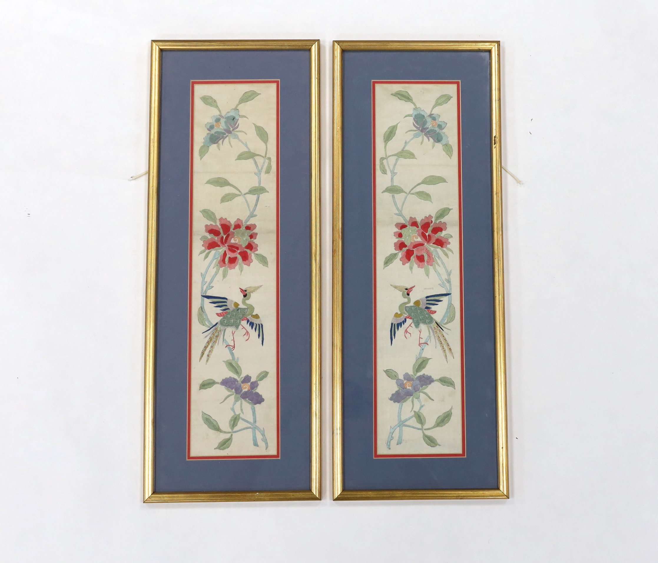 A pair of framed early 20th century Chinese cream silk polychrome silk embroidered sleeve bands, 11cm wide x 49cm long not including mount or frame